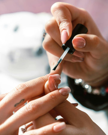 Top coat transparent appliqué sur une manucure élégante pour protéger le vernis et prolonger la tenue des ongles avec une finition brillante professionnelle.