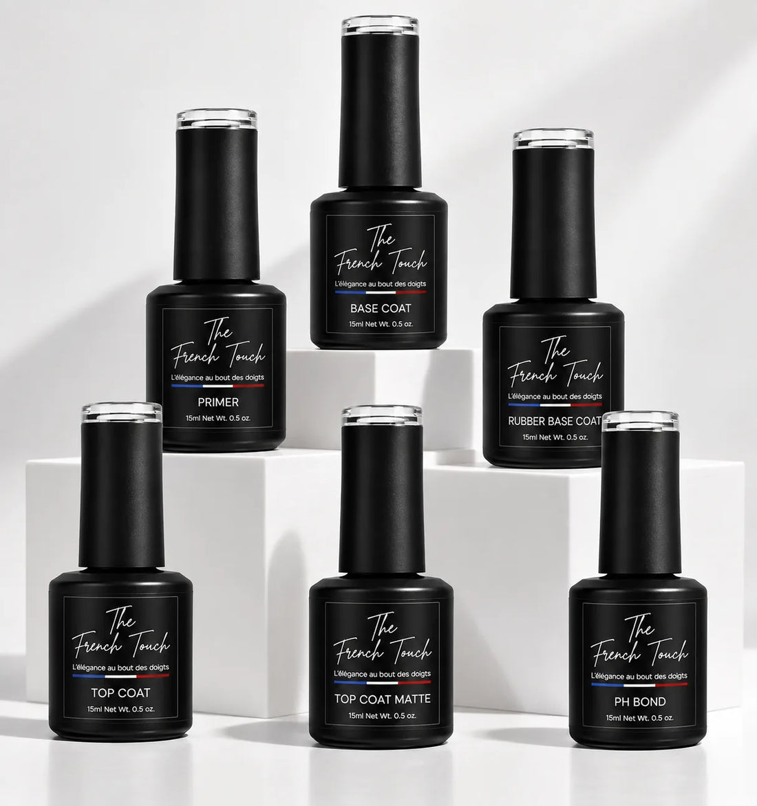 Six flacons The French Touch posés sur des socles blancs : primer, pH bond, base coat, rubber base coat, top coat et top coat matte pour vernis semi-permanent